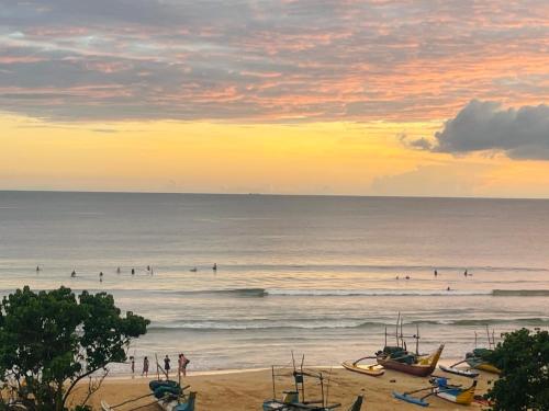 a group of people on the beach at sunset at Luminozo Beach Hotel in Weligama
