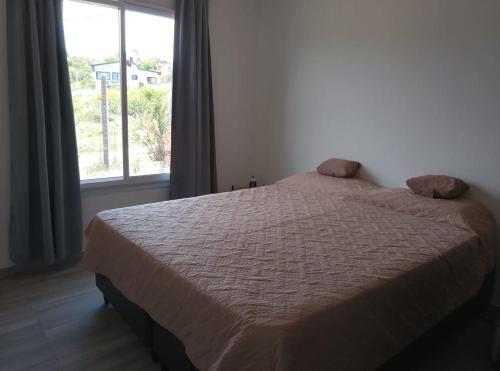 a bed in a bedroom with a large window at Mountain View & Comfort in Villa Santa Cruz del Lago