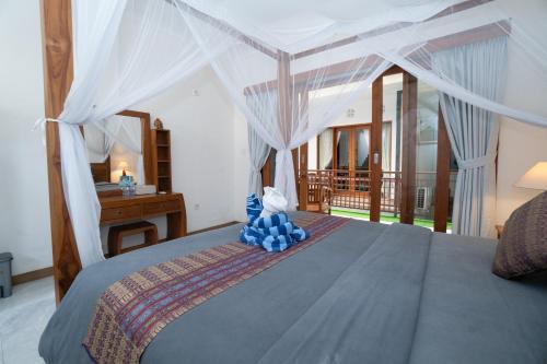 a bedroom with a bed with a blue teddy bear on it at Pak Vo House by The Travel Ubud Bali in Ubud