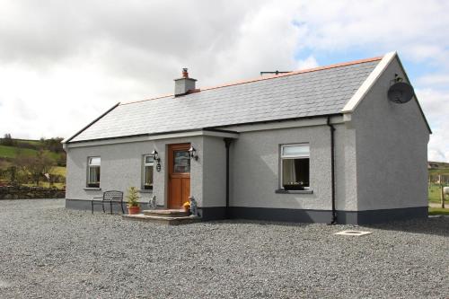 a small white house with a gravel driveway at Pat Larry's Cottage in Greencastle