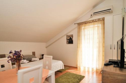 a living room with a table and a bed and a window at Apartmani P&M in Tivat