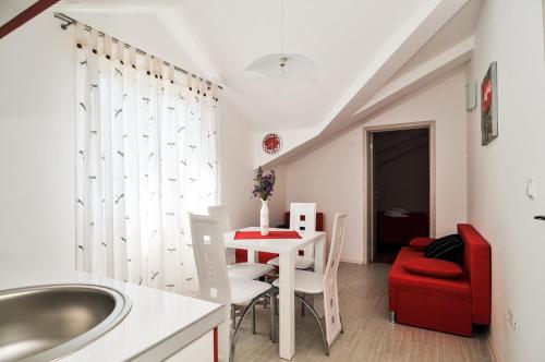 a bathroom with a sink and a table with a red chair at Apartmani P&M in Tivat