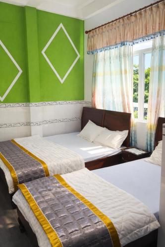 two beds in a room with green walls at Nam Phương Hotel Sa Đéc in Sa Ðéc