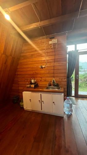a kitchen with a sink in a room with wooden walls at Padangsari Cabin 2 in Diyeng