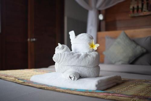 a stack of towels sitting on a bed with a flower at Pak Vo House by The Travel Ubud Bali in Ubud