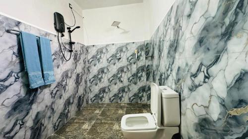 a bathroom with a white toilet and a marble wall at Paddy Wind Eco Lodge Sigiriya in Kibissa