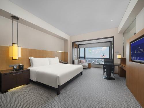 a hotel room with a white bed and a television at Jinling Hotel in Nanjing