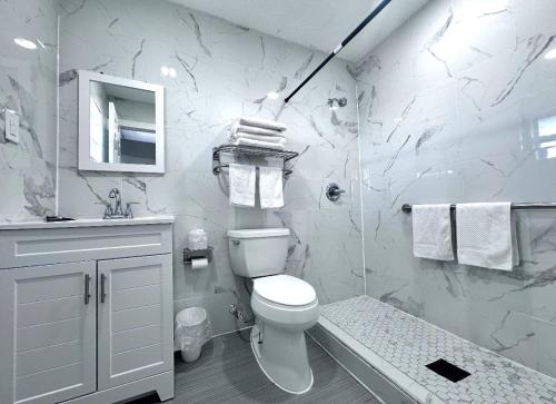 a white bathroom with a toilet and a shower at Lemon Bay Motel in Englewood