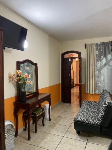 a living room with a table and a chair and a mirror at Hotel Real de Cortés in Xalapa