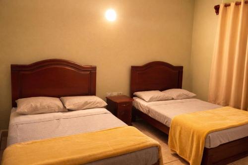 a bedroom with two beds with yellow sheets on them at Hotel Real de Cortés in Xalapa