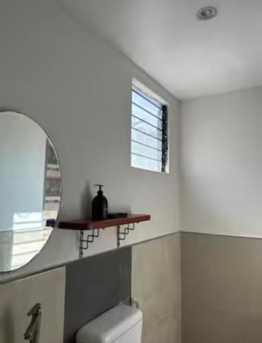 a bathroom with a mirror and a toilet and a window at Ashelma resort in Dauis