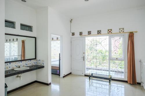 a bathroom with a sink and a mirror and a window at Urbanview Golden Barbie near Jawa Timur Park 2 in Tlekung