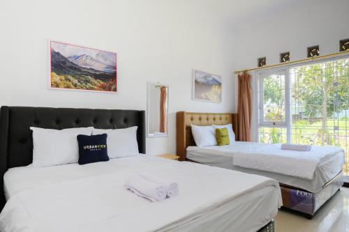 a bedroom with two beds and a window at Urbanview Golden Barbie near Jawa Timur Park 2 in Tlekung