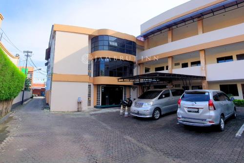 a dog standing in front of a building with two cars at Jambrut Inn in Jakarta