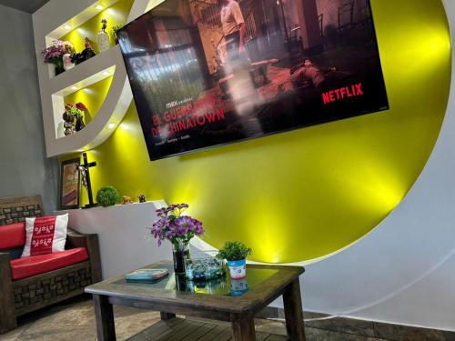 a living room with a table and a movie on the wall at Hotel Villa's Camargo in Ixmiquilpan