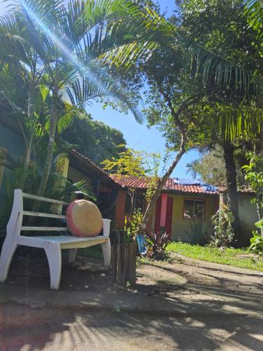 a bench with a hat on it in front of a house at EsPAÇO RUSTIK in Santa Cruz Cabrália