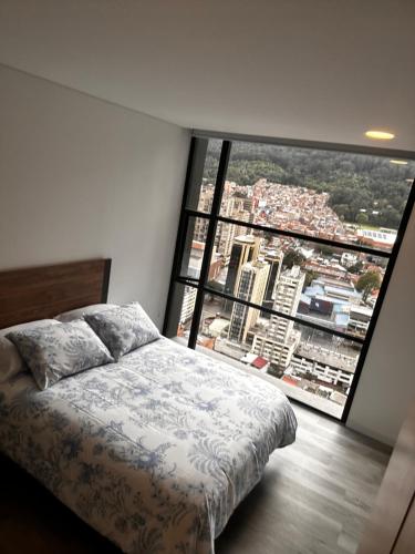 a bedroom with a bed and a large window at Aparta Suite Centro Internacional Edificio 33DC Piso 29 Estación Trasmilenio Calle 34 in Bogotá
