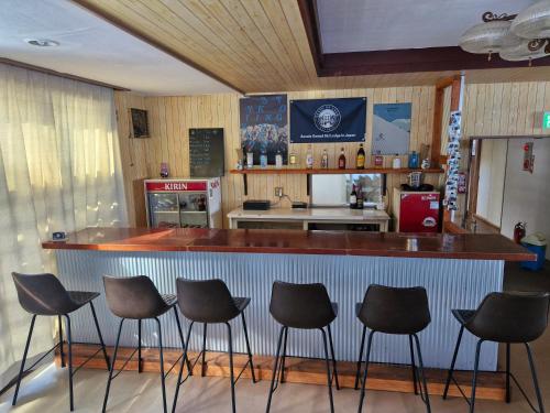 a bar with four stools in a kitchen at Sanso On Snow in Nagano