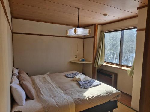 a small bed in a room with a window at Sanso On Snow in Nagano