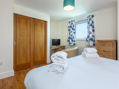 a bedroom with a white bed and a television at Peregrine in Poole