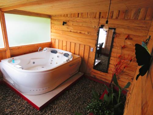 a bath tub in a wooden room with a window at Cabañas Sumak Kawsay in Colón