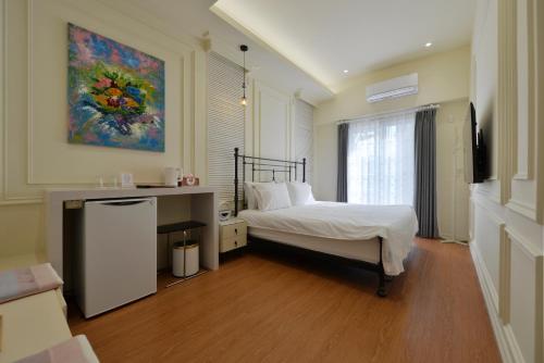a bedroom with a bed and a painting on the wall at Station B&B in Tainan