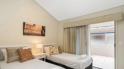 a bedroom with two beds and a window with a balcony at Pipi's On The Beach 1 - 2 Fletcher Street in Byron Bay