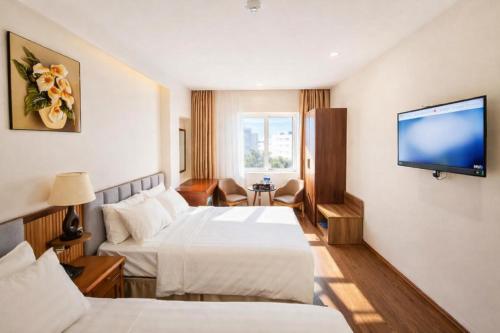 a hotel room with two beds and a flat screen tv at Xavia Hotel Quy Nhơn in Quy Nhon