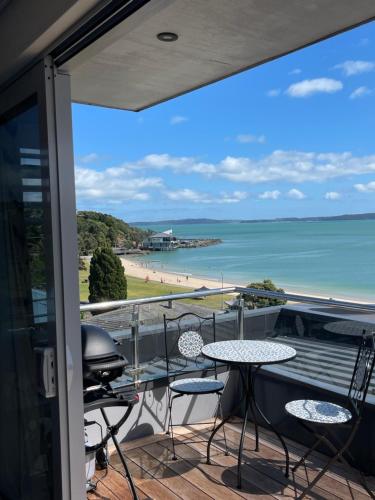 a balcony with a table and chairs and a view of the beach at Maraetai views in Auckland