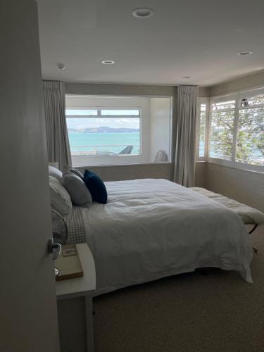 a bedroom with a large bed with a large window at Maraetai views in Auckland