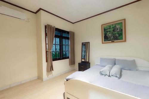 a bedroom with a white bed and a window at Imah Budi Luhur in Bandung
