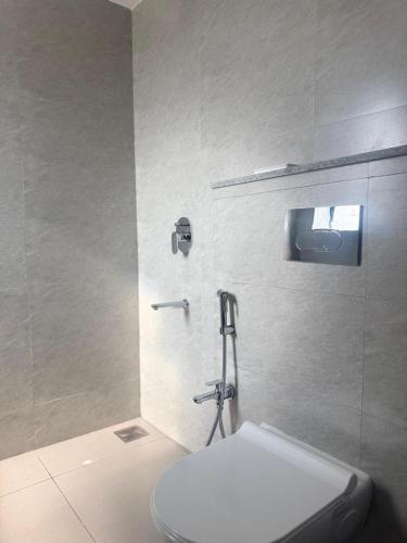 a white bathroom with a toilet and a shower at Henmil Hideaway in Anjuna