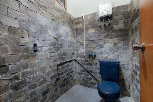 a bathroom with a blue toilet and a stone wall at Imah Budi Luhur in Bandung
