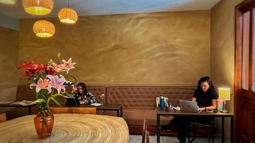 two women sitting at tables in a restaurant with a laptop at Hostal Central Oaxaca in Oaxaca City