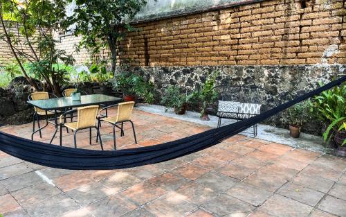 a hammock on a patio with a table and chairs at Shanti Home in Tepoztlán