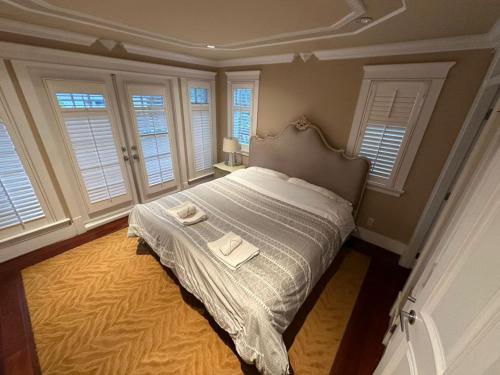 a bedroom with a bed with a white blanket and windows at Luxury Room with Private Washroom in Prime Location in Vancouver