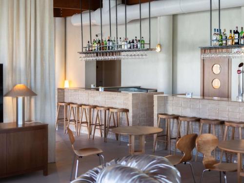a restaurant with a bar with wooden tables and chairs at Ibis Valencia Alfafar in Alfafar