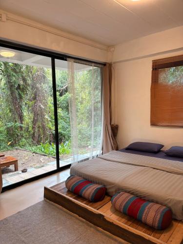 a bedroom with a bed and a large window at Lakehouse in the Old Rainforest in Ko Phangan