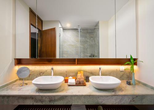 a bathroom with two sinks and a mirror at TUI BLUE Angkor Grace Wellness Resort in Siem Reap