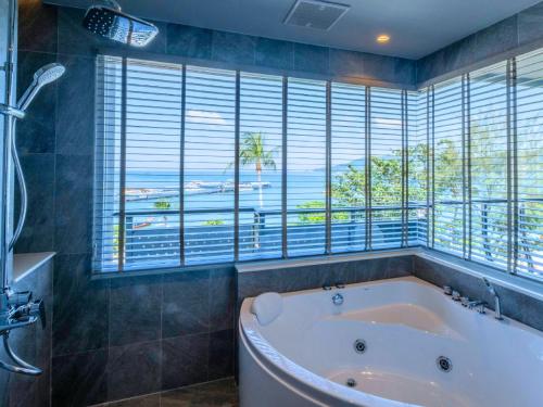 a bath tub in a bathroom with a large window at Homm Bliss Southbeach Patong in Patong Beach