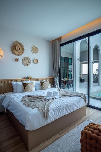 a bedroom with a large bed and a large window at Gam-Hom Poolvilla ชะอำ in Ban Hua Phrong