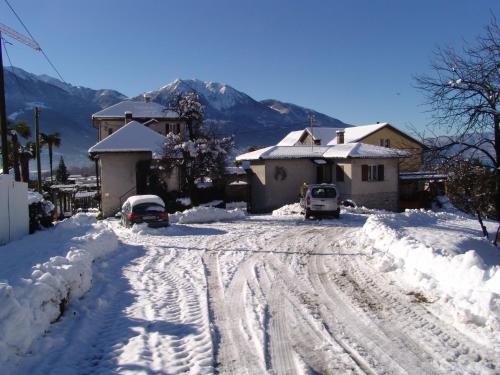 a street covered in snow with a house and cars at Casa Perini in Tenero