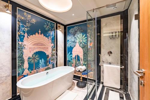 a bathroom with a tub and a wall mural at Acacia Somgarh Udaipur in Udaipur