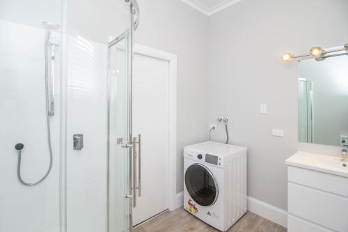 a bathroom with a washing machine and a shower at Bolton Street Cottage in Lower Hutt