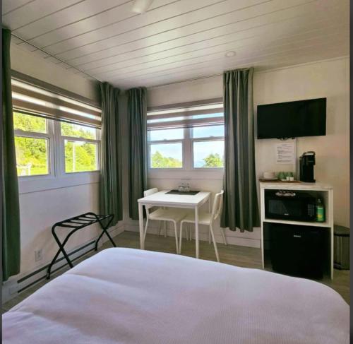 a bedroom with a bed and a table and window at En Route Vers l'Infini in Perce