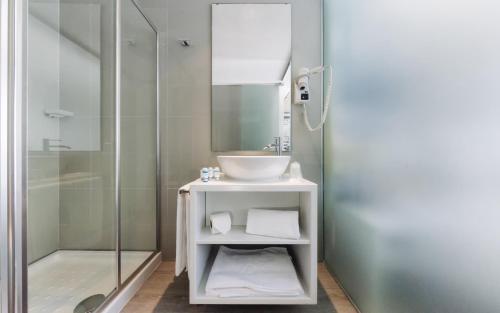 uma casa de banho com um lavatório e uma cabina de duche em vidro. em Lisbon Sao Bento Hotel em Lisboa