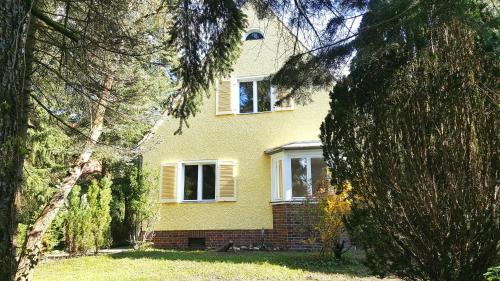 a yellow house with a window and trees at Ferienhaus Sanssouci in Stahnsdorf