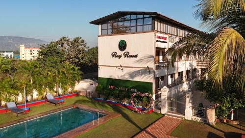 a building with a swimming pool in front of a building at Raaj Resort in Panvel