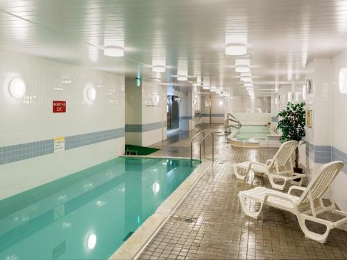 a swimming pool in a building with chairs around it at Nara Royal Hotel in Nara