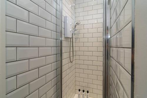 a bathroom with a shower with white tiled walls at Spacious 3-Bed, Town Centre, Parking, Near Beach in Bournemouth